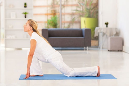 Une femme fait du yoga dans une chambre en pose fente avant