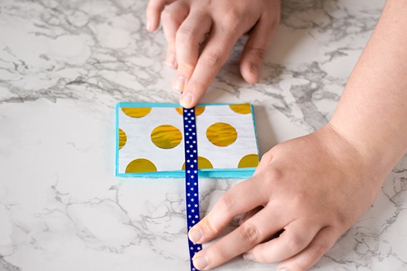 Le ruban bleu foncé à étoiles blanches est collé sur le papier d'emballage collé sur la cartoline