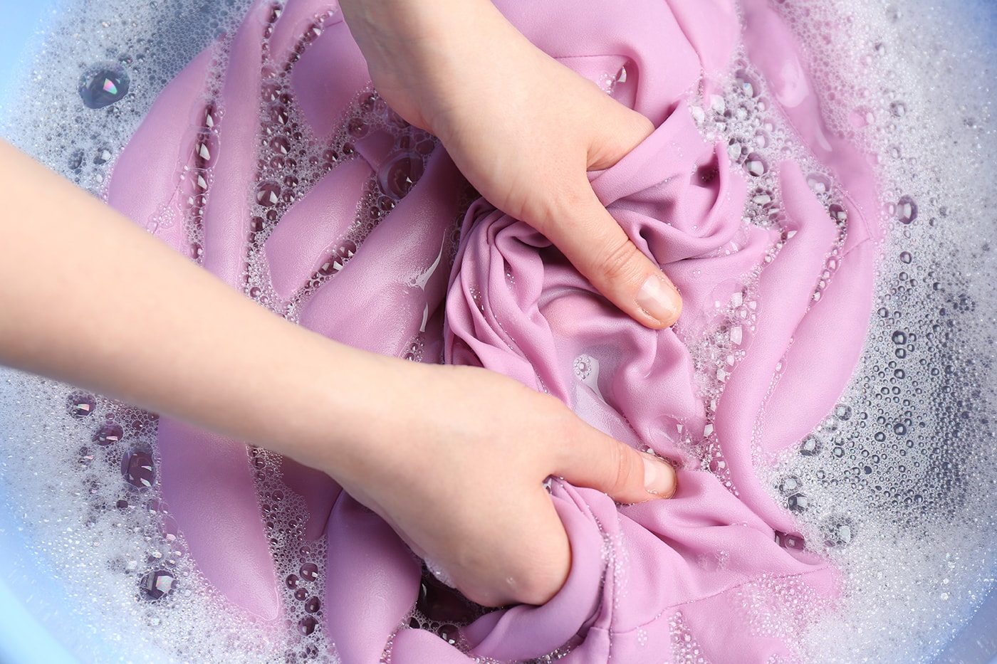 Ein Kleidungsstück wird von Hand in einem Eimer gewaschen, um Wasserflecken zu entfernen. 